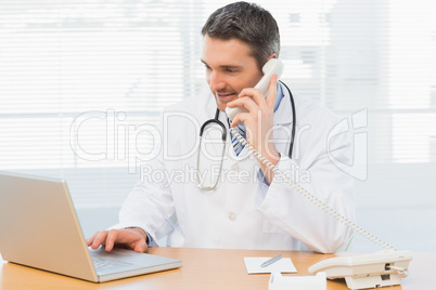 Concentrated doctor using laptop and phone