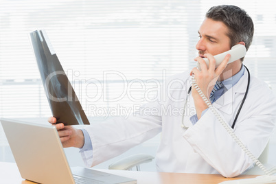 Serious male doctor examining x-ray while on call