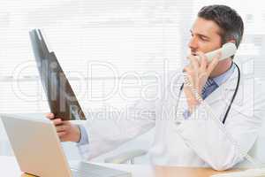 Serious male doctor examining x-ray while on call