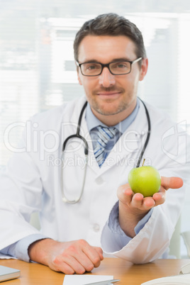 Portrait of a smiling male doctor holding an apple