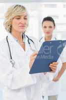 Female doctor reading reports with colleague in hospital