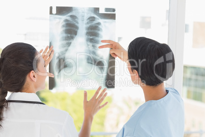 Rear view of two female doctors examining x-ray