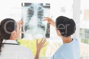 Rear view of two female doctors examining x-ray