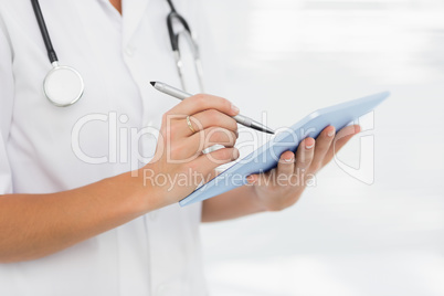 Mid section of a female doctor using digital tablet