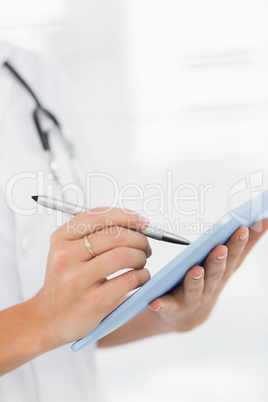 Mid section of a female doctor using digital tablet