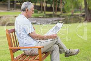 Relaxed senior man reading newspaper at park