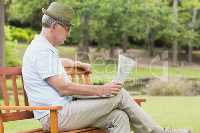 Relaxed senior man reading newspaper at the park