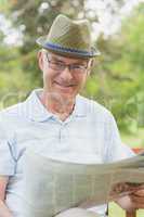 Senior man reading newspaper at park