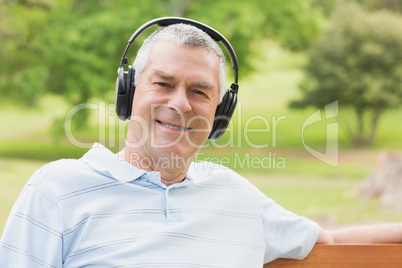 Smiling senior man with headphones at the park