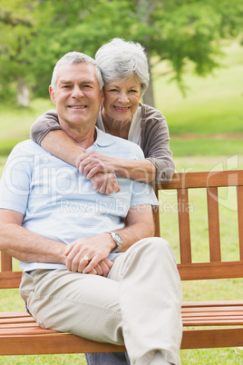 Senior woman embracing man from behind at park