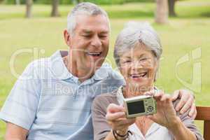 Cheerful senior couple photographing themselves at park