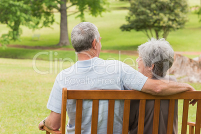 Rear view of senior couple sitting on bench at park