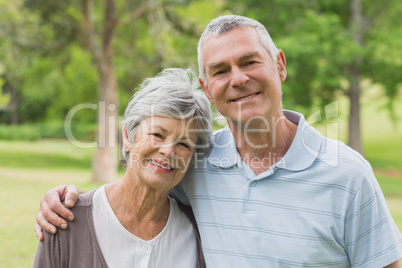 Portrait of a senior couple with arms around at park