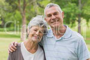 Portrait of a senior couple with arms around at park