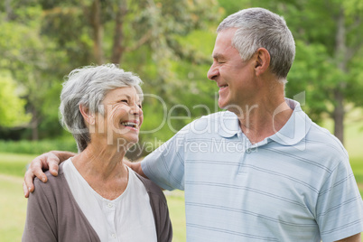 Happy senior couple with arms around at park