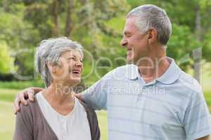 Happy senior couple with arms around at park