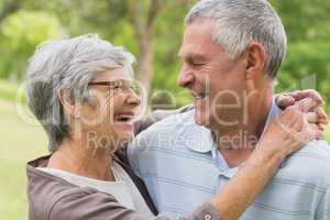 Happy senior woman embracing man at the park