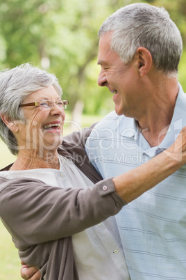 Happy senior woman embracing man at park