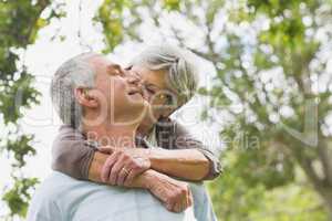 Senior woman embracing man from behind at park