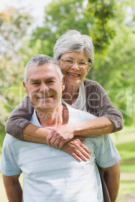 Senior woman embracing man from behind at park