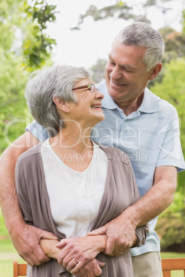 Senior man embracing woman from behind at park