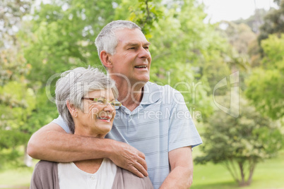 Senior man embracing woman from behind at park