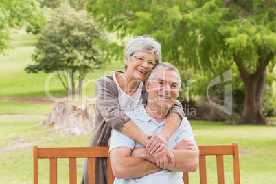 Senior woman embracing man from behind at park