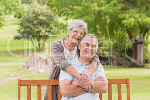 Senior woman embracing man from behind at park