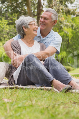 Senior man embracing woman from behind at park