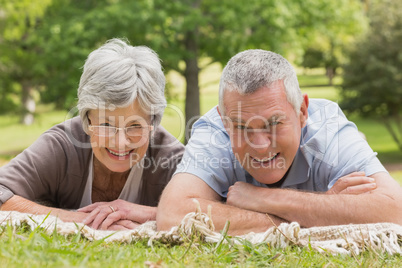 Portrait of senior couple lying at park