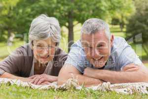 Portrait of senior couple lying at park