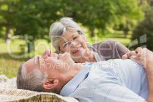 Side of a senior couple lying at park