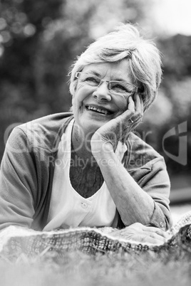 Smiling senior woman lying at park