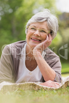 Smiling senior woman lying at park