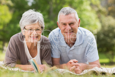 Smiling relaxed senior couple lying in park