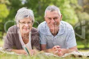 Smiling relaxed senior couple lying in park