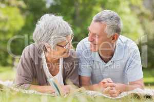 Smiling relaxed senior couple lying in park