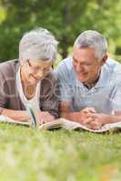 Smiling relaxed senior couple lying in park