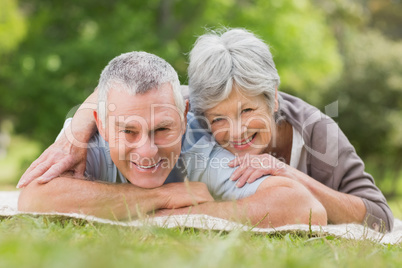 Smiling relaxed senior couple lying in park