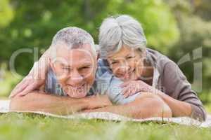 Smiling relaxed senior couple lying in park