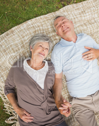 Smiling relaxed senior couple lying in park