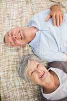 Smiling relaxed senior couple lying in park