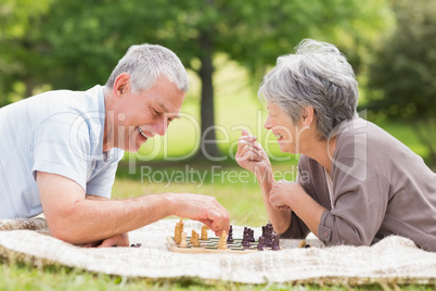 Happy senior couple playing chess at the park