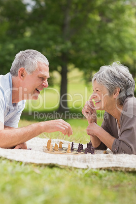 Happy senior couple playing chess at park