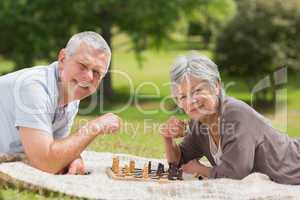 Happy senior couple playing chess at park