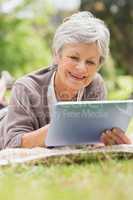 Smiling senior woman using digital tablet at park