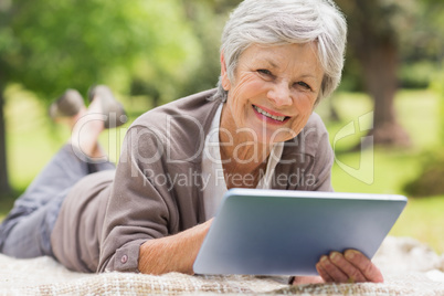 Smiling senior woman using digital tablet at park