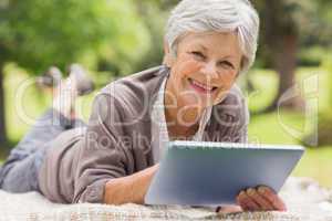 Smiling senior woman using digital tablet at park