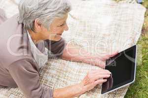 Smiling senior woman using digital tablet at park