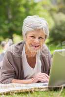 Smiling senior woman using laptop at park